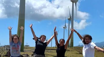 students jump abroad by wind turbines