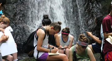 High school students journaling by a waterfall in Monteverde