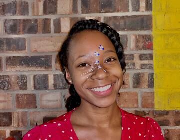 Destiny with her face painted by a woman who also does beadwork. 