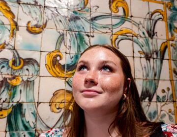 Student next to a tile mural
