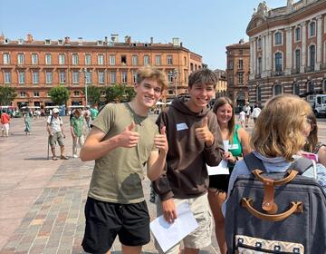 Two students smiling and giving a thumbs up
