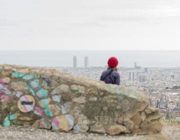 Student in red hat looking down at city skyline on hike