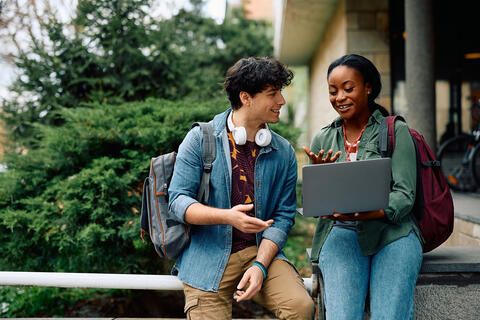 Two students looking at a laptop together on campus