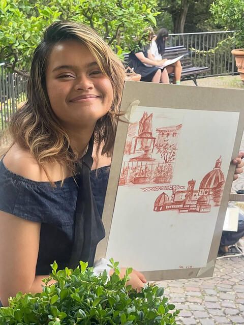 Student smiling while showing off her art on sketchpad