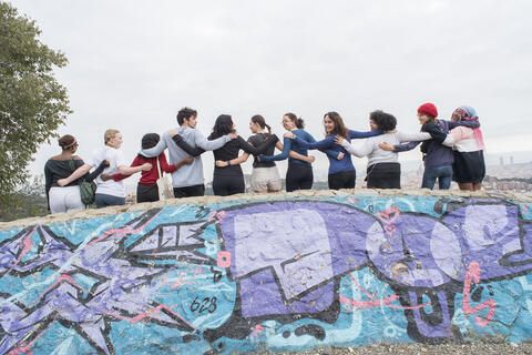 Students on study abroad program posing above street art 