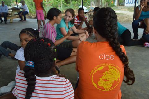 Student sitting with kids while volunteering abroad