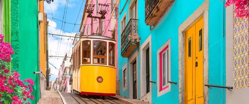 a yellow tram car going downhill in lisbon