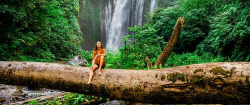 monteverde woman on log in front of a waterfall