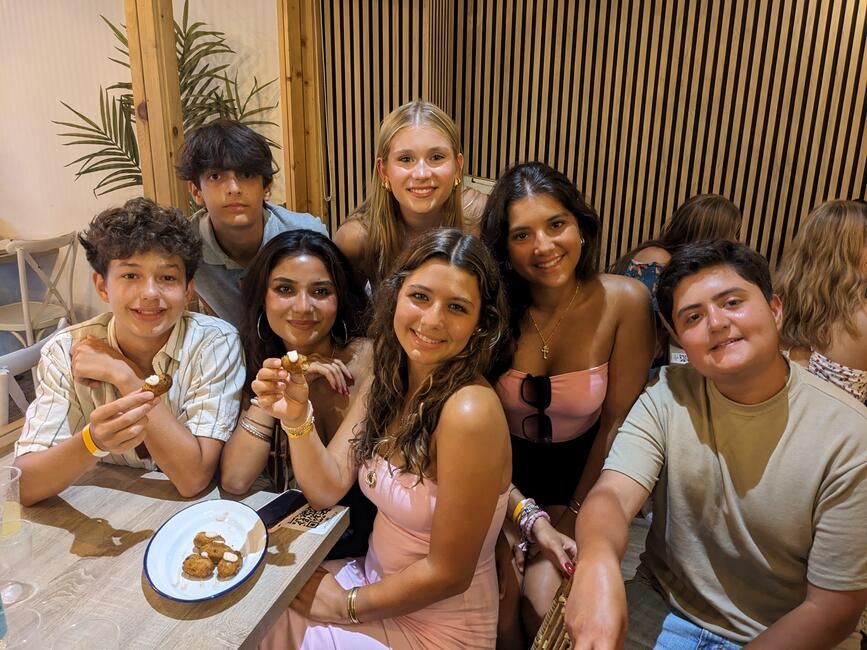 Students sitting at a table with croquettes smile