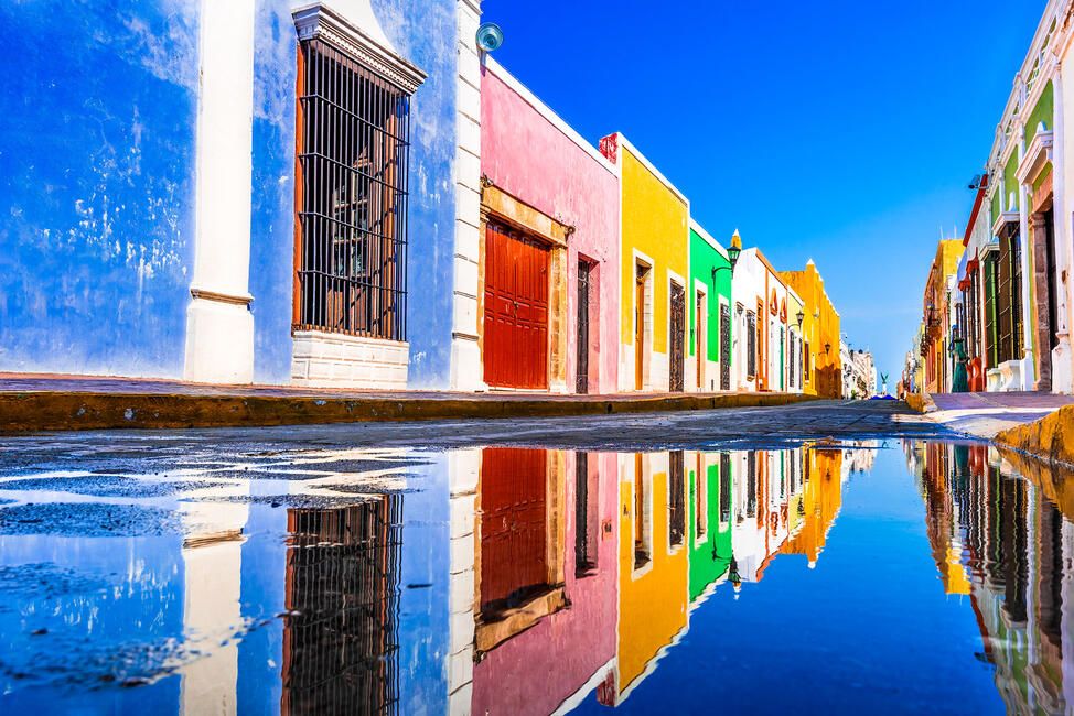 colorful buildings in yucatan mexico reflected in a puddle of water