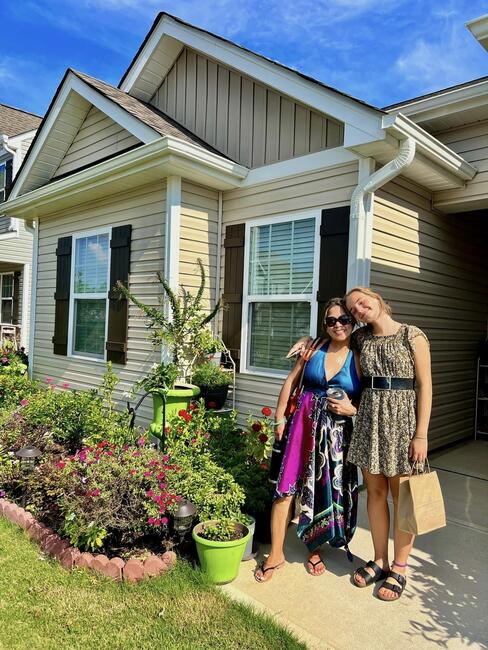 A host mom and daughter pose in front of their house.