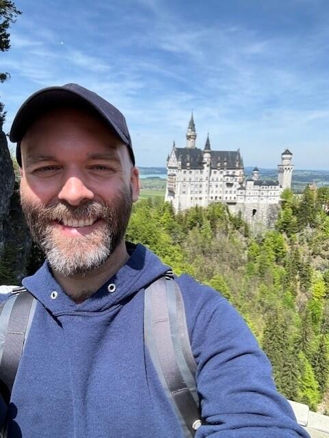 a selfie of a man in front of a german gothic castle