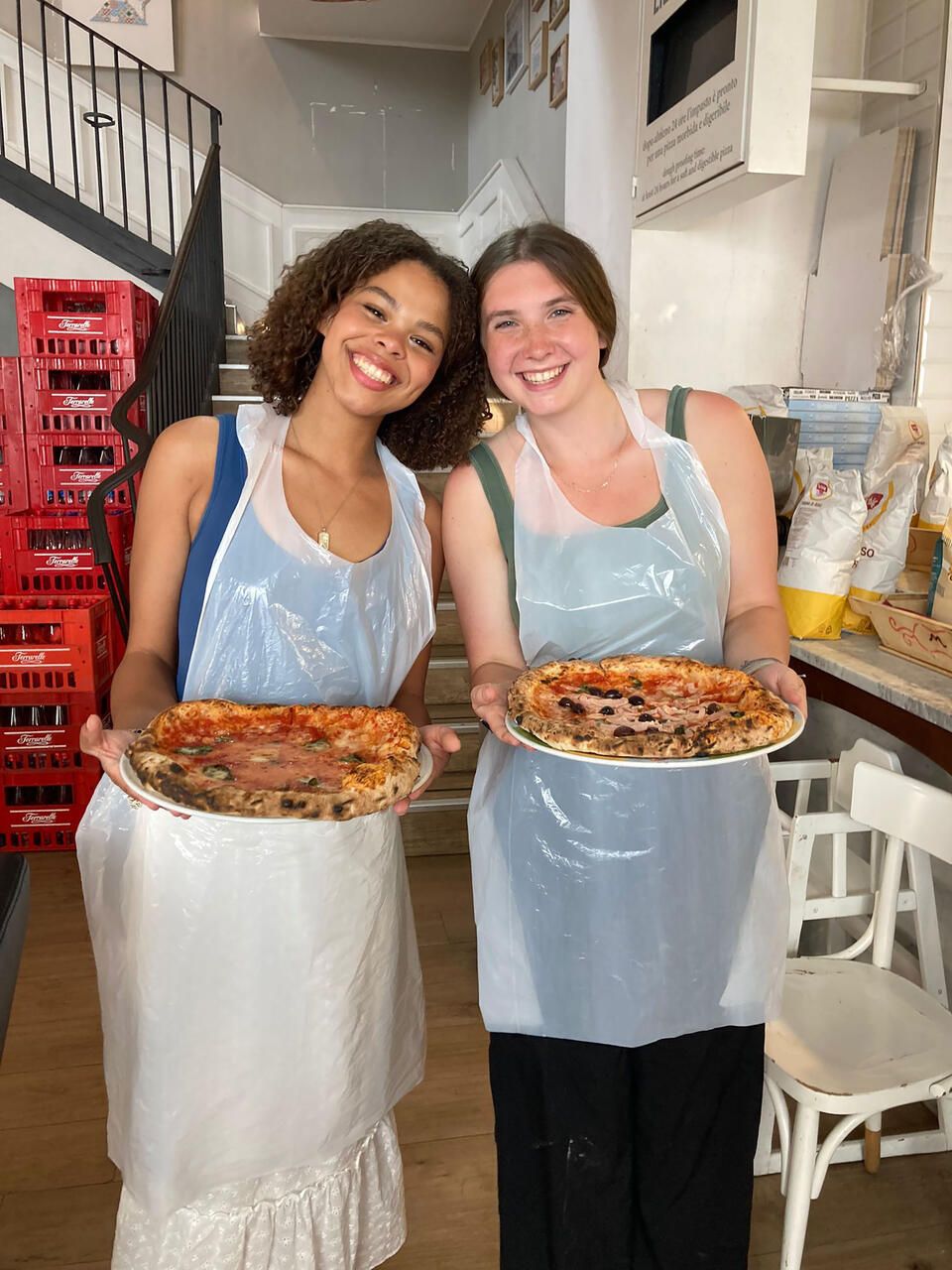 Two students holding up pizza they baked in a cooking class in Rome