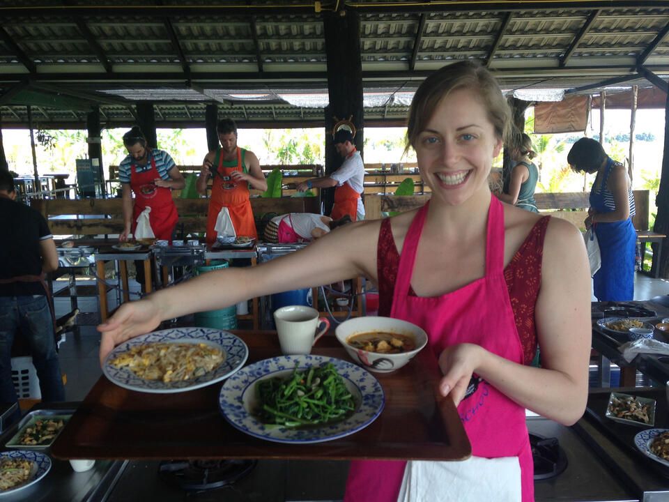 Young woman in Thailand holding up plates of food